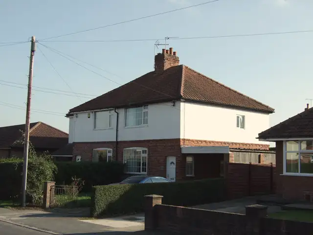 Semi-detached brick and render house with a hipped tiled roof and chimney on School Lane, Copmanthorpe