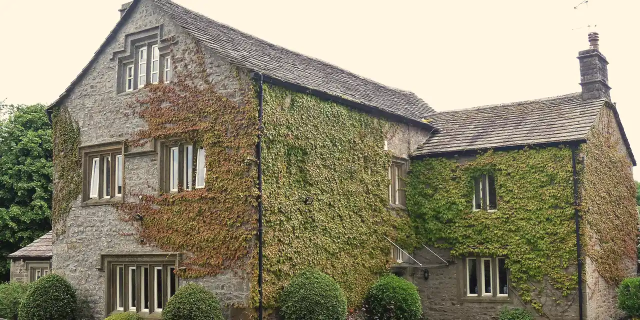 Seventeenth-century stone house with a graded stone slate roof and ivy-covered walls in Gargrave, North Yorkshire